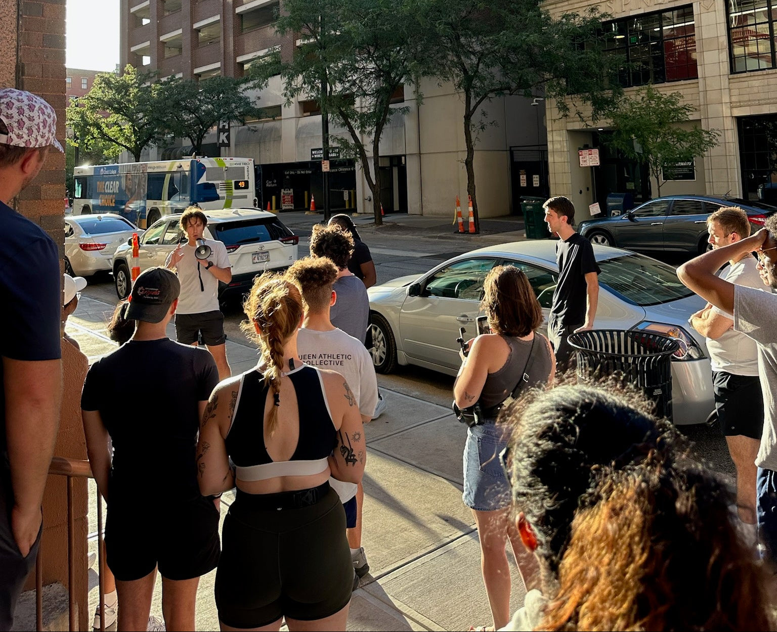 Group of people standing on a city street with buildings and cars in the background